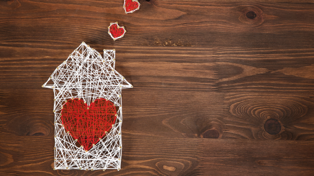 Rappresentazione di una casa con cuori realizzata con fili e chiodi