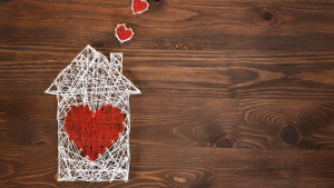 Rappresentazione di una casa con cuori realizzata con fili e chiodi