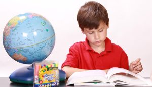 bambino che studia con mappamondo accanto