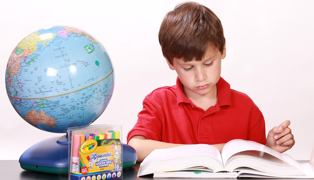bambino che studia con mappamondo accanto