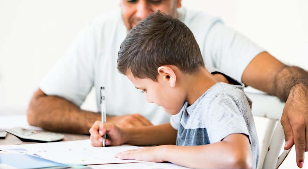 bambino che fa i compiti aiutato da un adulto