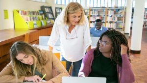 due adulte su una scrivania accanto ad insegnante