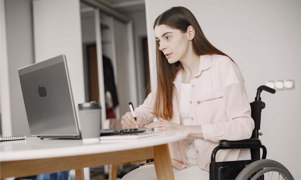 donna sulla sedia a rotelle che lavora al computer