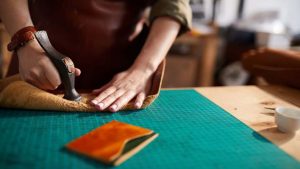 mani che lavorano la pelle con un martello