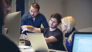 tre ragazzi che stanno lavorando insieme al computer