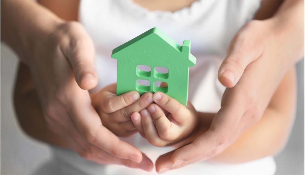 mani di bambina che tenfono una casa e mani di adulto